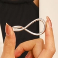 Macro shot of silver infinity ring with polished mirror finish held by hand - Infinity Symbol Style (Z-626)