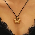 Gros plan d'un pendentif étoile en or mat sur un cordon noir porté par un mannequin - Style Étoile Or Mat (G-393)