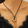Détail d'un collier avec pendentif fleur en or mat et cordon noir porté par un mannequin - Style Fleur Or Mat (G059)