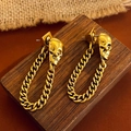 Gotische Vintage Totenkopf-Ohrhänger in Gold mit Gliederkette auf Holzdekor - Totenkopf Kette Ohrstecker / Altgold