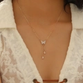 Elegant gold butterfly pendant necklace with sparkly tassels on a model's neck - Gold Butterfly Tassel Style (11999)