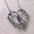 Macro detail of silver thorn heart pendant with grey crystal pillar on a metal chain - Gunmetal