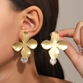 Detailed close-up of large golden metal petal earrings with white baroque pearl pendants - Light Matte Gold Style (A-1175)