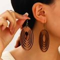 Close-up of model wearing large bohemian hollow oval wooden earrings with natural grain - Wood Hollow Oval Drop Earrings (5039) / Dark Brown
