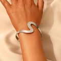 Polished silver wave cuff bracelet shown on wrist against beige silk background - Silver Wave Pattern Open Bracelet (26)