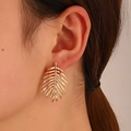 Elegant gold-tone palm leaf earrings worn by a model for a tropical minimalist look - Gold Palm Leaf Shape (WG-0344)