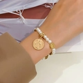 Detalle de pulsera de rosario de perlas con colgantes de monedas vintage doradas en la muñeca - Rosario de Cuentas de Oro KC (04 oro KC K-180)