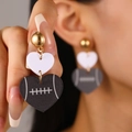 Gros plan sur des boucles d'oreilles cœur en acrylique avec motif de football américain - Boucles d'oreilles pendantes en acrylique à trois couches en forme de cœur / Noir (Texture Rugby)