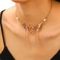 Golden heart necklace with pink gemstone, pearl accents, and fringe tassels on model - Gold Style (Pink Stone)