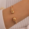 Golden punk cuff bracelet featuring dual skull accents in a vintage metallic finish - Open Bangle (G-564) / KC Gold (Double Skull Open Bangle)