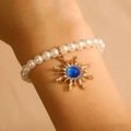 Bracciale di perle vintage con ciondolo a sole dorato e gemma blu centrale elegante - Bracciale Oro Blu