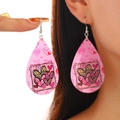 Detail of tear-drop earrings with pink heart patterns and silver hooks on model - Pink