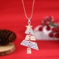 Macro detail of mixed metal Christmas tree pendant with golden star on festive background - Christmas Tree Pendant Necklace (K-432) / Gold and Silver