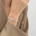 Primer plano de una pulsera de diamantes de imitación usada por modelo en traje formal - Estilo Entrelazado de Ondas (K-1539)