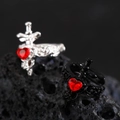 Detailed view of Gothic sword rings with red heart crystals on black volcanic rock - Sword Through Heart Ear Clips (Black & White Pair)