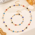 Détail d'une parure dorée Mauvais Œil avec perles en émail colorées et fermoirs mousqueton - Ensemble Bracelet + Collier / Parure Bracelet + Collier Mauvais Œil Doré