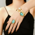 Goldenes Set aus Armreif und Ring mit Barockperle und grünen Edelsteinen am Modell - Set aus künstlichen Perlenringen und Armbändern / Blau