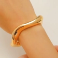 Chic golden wavy wide open bangle with a high-polished finish on a model's wrist - Wavy Bangle (4347) / KC Gold