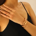 Macro detail of high-polish gold spiral ring and wide cuff bracelet set on a model - Bracelet and Ring Set in Gold (5541+5516)