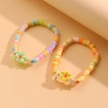 Detalle de pulseras bohemias de cuentas heishi con dijes de estrella de mar y plumeria - Juego de 2 Pulseras Florales
