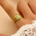 Détail macro d'une bague vintage dorée avec pierre ovale émeraude et décor dentelle - Style Goutte Ovale à Texture Mate (10595)