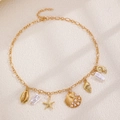 Collier doré avec pendentifs étoile de mer et coquillage, perles sur tissu texturé - Style Coquille de Monnaie (1666)