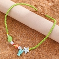 Detail of beaded sea shell necklace with blue fish and starfish on beach sand - Green Fish Beaded Style (DZ-533)