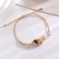 Detail of a handmade ocean-style rope bracelet with starfish beads and shells - Coffee