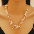 Collana boho dorata con perle, conchiglie e ciondolo a stella marina su modella - Collana con Conchiglia di Conch di Consistenza Naturale (3255) / Oro