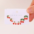 Three pairs of cherry stud earrings in red and green enamel on a jewelry display card - Cherry Stud Earrings (25010522) / Light Gold (X301)