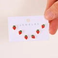 Three pairs of cute red strawberry alloy stud earrings on a white jewelry card display - Light Gold (WG-0828)