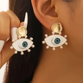 Macro detail of Evil Eye earrings with blue zircon and white pearl accents on golden base - 03 KC Gold Style (11138)
