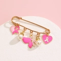 Detailed view of pink ribbon charms and white pearls on a gold-tone safety pin brooch - Pink Heart Butterfly Style