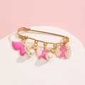 Detail of pink breast cancer awareness ribbon charms and white pearls on a gold safety pin - Pink Ribbon Wing Style