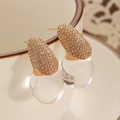 Detailed macro view of gold-tone teardrop earrings with crystals on a white ceramic cup - Zirconia Inlaid Water Drop (9710) / KC Gold (Inlaid Zirconia Style)