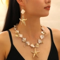 Dettaglio di un set collana da spiaggia con stelle marine dorate, conchiglie e perle - Set a Tema Oceano Iridescente