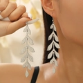 Détail des boucles d'oreilles longues feuilles argentées texturées portées par un mannequin - Pendant à Feuilles Multi-sections / Or blanc