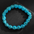 Gros plan détaillé du bracelet en perles de crâne turquoise sur une pierre noire mate - Crâne de Couleur Cyan Brillant