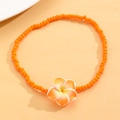 Detalle de tobillera de cuentas naranjas con flor de frangipani para estilo playero - Naranja