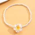 Primer plano de tobillera bohemia de cuentas blancas con flor de plumeria sobre fondo naranja - Blanco