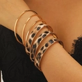 Detail view of 8-piece leopard print and gold metal stacked bracelets on female model's arm - Simple Leopard Style (A-1159)