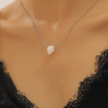 Close-up of minimalist silver chain with white skull pendant on woman neck - White K (5527)