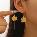 Macro close-up of golden maple leaf earrings with long chain tassels worn by a female model - Gold Maple Leaf Drop Earrings (2333)