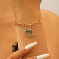 Detailed close-up of golden evil eye bracelet with white zircon inlay on model's wrist - Bracelet / Gold