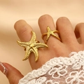 Detail of 18K gold-plated starfish rings with realistic texture on a warm background - Starfish Combo Style (19) / 2 Pcs/Set / Gold