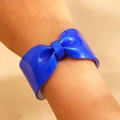 Detailed view of a bright blue resin bow bracelet with glitter on a model's wrist - Blue