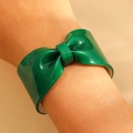 Macro detail of sparkly dark green resin bow bracelet featuring glitter and polished finish - Green
