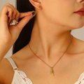 Elegant gold hollow rose earring and necklace set on model with a warm beige background - Rose Necklace, Stud Earrings / Gold Rose 2-Piece Jewelry Set (7812)