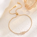 Detailed macro of golden double heart bracelet with cubic zirconia and adjustable slide closure - Interlinked Hearts Style
