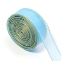 Makro-Detail von hellblauem Organzaband auf Rolle mit elegantem Gold-Drahtrand für DIY - See Blau